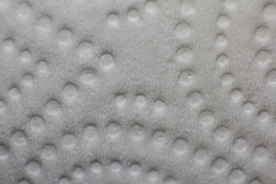 Close-up textured paper towel surface with raised circular pattern, abstract macro detail of absorbent material