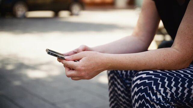 Close-up of a woman holding and using a smartphone outdoors. Mobile communication, digital technology, social media, internet connectivity and modern lifestyle concept.4K.