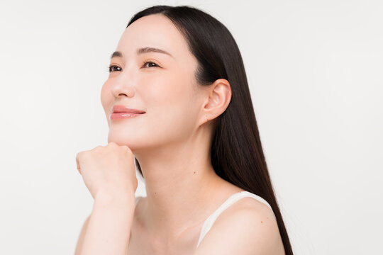 顔に手を添える黒髪ストレートヘアの若い日本人女性。スキンケアイメージ。