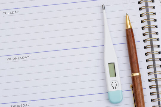 Blank daily planner with pen and thermometer for scheduling healthcare appointments
