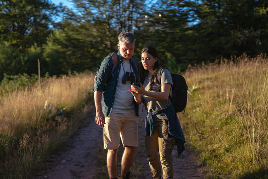 Couple navigating hiking trail using smartphone during outdoor adventure