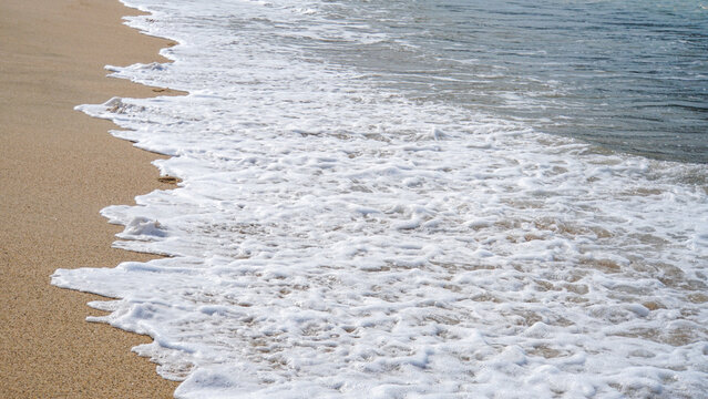 渚に打ち寄せる白い泡の波と砂浜