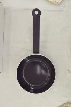 Black frying pan viewed from above against a light background, showcasing its circular cooking surface and functional handle.