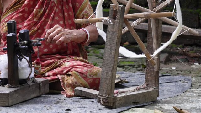 Artisan spinning natural fiber thread on traditional wooden charkha