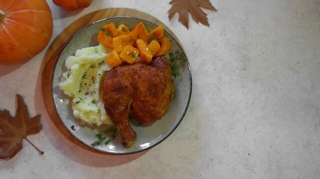 Roasted chicken quarter with glazed pumpkin, herbs and mashed potato, top view. Portion of festive autumn meal for Thanksgiving. Healthy seasonal food.