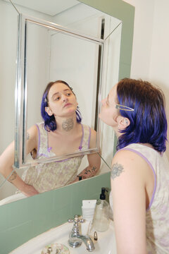 Alternative person looking at themselves in the mirror in the bathroom