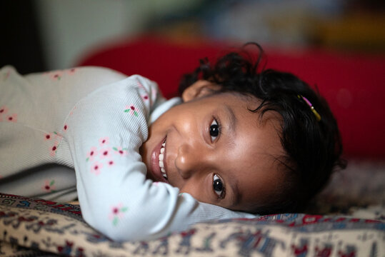 Toddler lying on bed looking to camera and laughing 