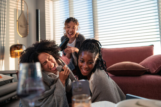 Three friends have a joyful karaoke at home.