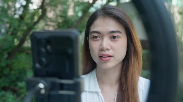 Woman presents directly to a smartphone camera outdoors, speaking with natural facial expressions and hand gestures for social media, online communication, and digital content