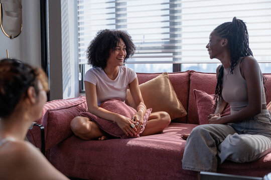 Three friends enjoy a happy conversation on a sunlit sofa.