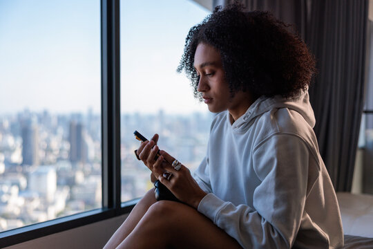 Woman Using Smartphone While Relaxing on Bed in High Rise Apartment