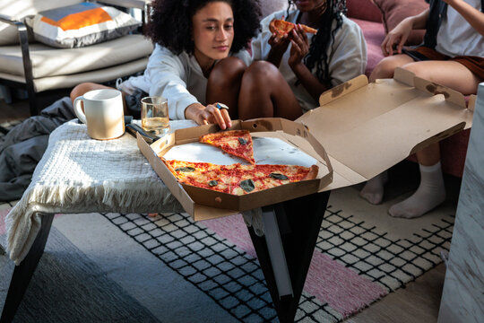 Friends share pizza during a relaxed, casual get together.