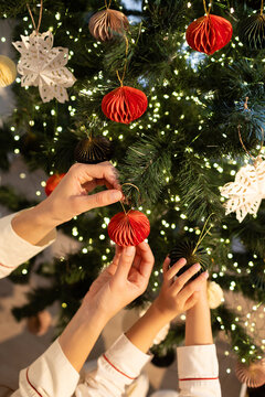 Anonymous mother and daughter hands decorating Christmas tree 