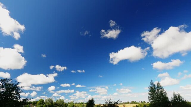 Summer Cloud Timelapse With Fluffy White Cumulus Clouds Moving Across Bright Blue Sky Above Distant Horizon