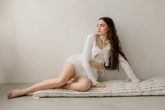 Beautiful young woman at home in fancy white clothes