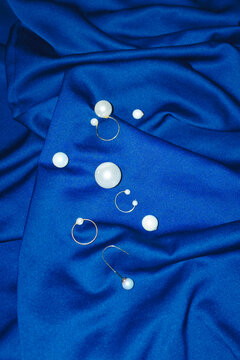 Classic white pearl jewellery on blue silk with hard direct flashlight