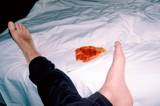 pepperoni pizza framed between the outstretched legs of a man