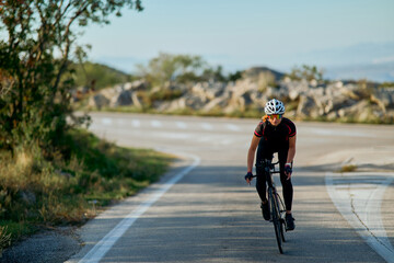 Naklejka premium Female Cyclist Riding Road Bike on Winding Country Road During Morning Training Session