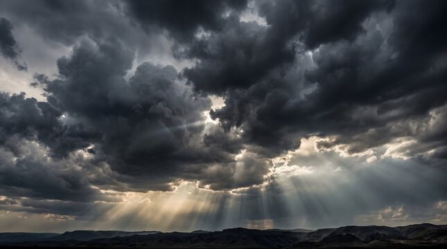 Sunlight rays streaming through dark storm clouds over a vast rolling mountain range landscape with above silhouetted mountain sunlight beams break