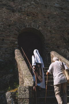Nun and elderly man climbing stone steps to an old stone archway