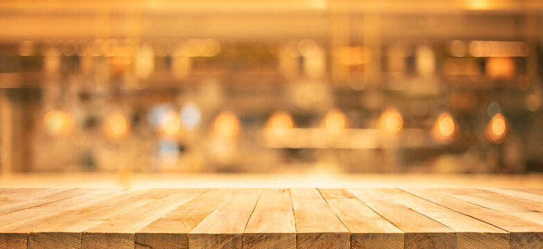 Selective focus.Wood table top (Bar) with blur light gold bokeh in dark night cafe,restaurant
