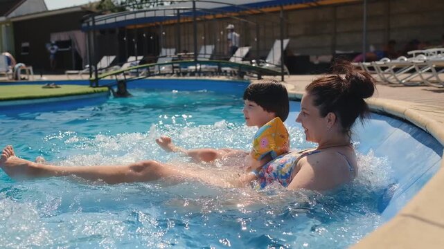 Mother and little son relaxing in outdoor swimming pool whirlpool jacuzzi