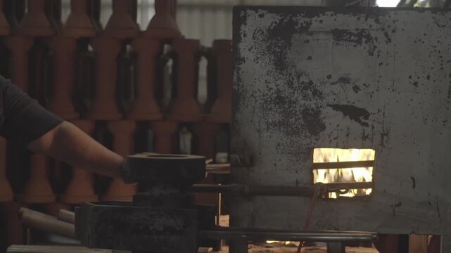 Gloved hand operating hot industrial furnace in factory
