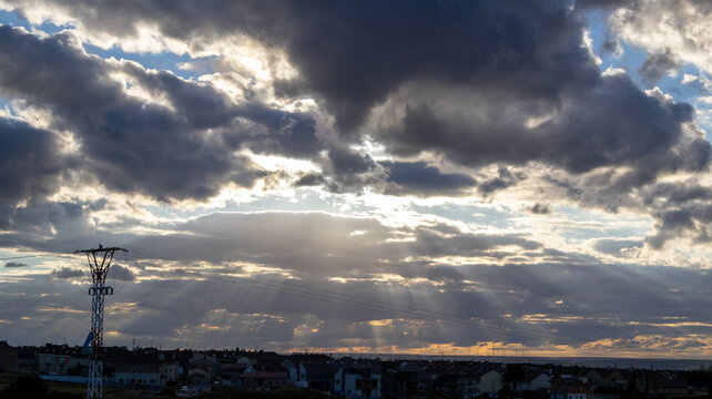 Cielo con nubes densas y rayos de luz sobre el horizonte urbano