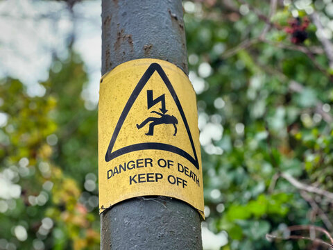 Yellow Danger of Death Keep Off High Voltage Warning Sign on Utility Pole