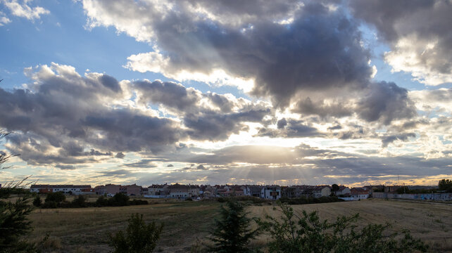 Cielo nublado con rayos de sol sobre el horizonte urbano
