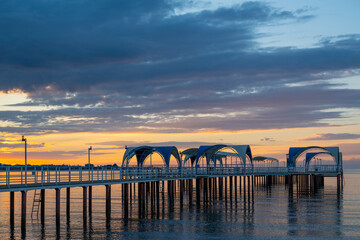 Fototapeta premium A metal pier set against the backdrop of a picturesque sunrise over Lake Issyk-Kul, near the Kyrgyz city of Cholpon-Ata.