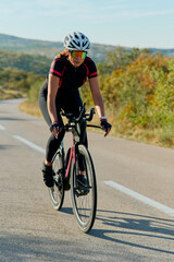 Naklejka premium Female Cyclist Training on Open Road With Helmet and Sunglasses - Outdoor Road Cycling Fitness