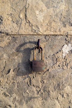 A padlock hanging on an old wall casting a shadow