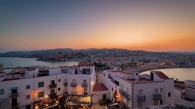 Peniscola old town pan view at dusk, Castellon Spain. Mediterranean coast, white houses, beach bay and sunset sky from fortress top. High quality 4k footage