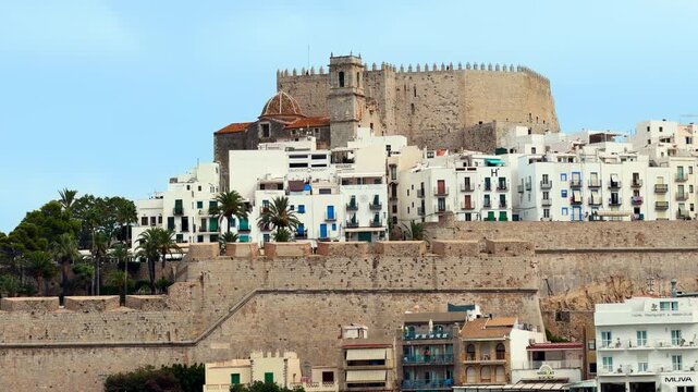 Peniscola old town fortress pan view, Castellon Spain. Historic stone fortification wall, white houses and church under blue sky. High quality 4k footage