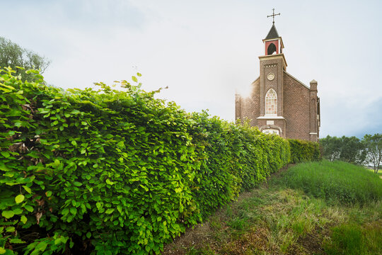 Sunlight streams through clouds, illuminating a lone brick church.