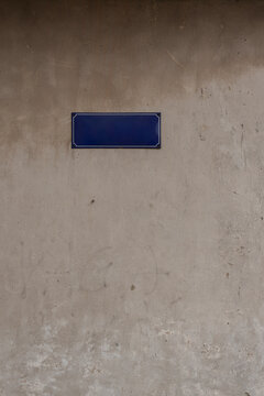 Blank blue street sign mounted on a weathered concrete wall with copy space