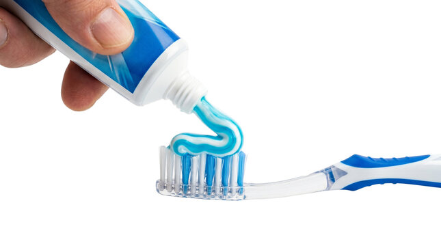 Hand squeezing fresh blue and white striped toothpaste onto soft plastic bristles of manual toothbrush