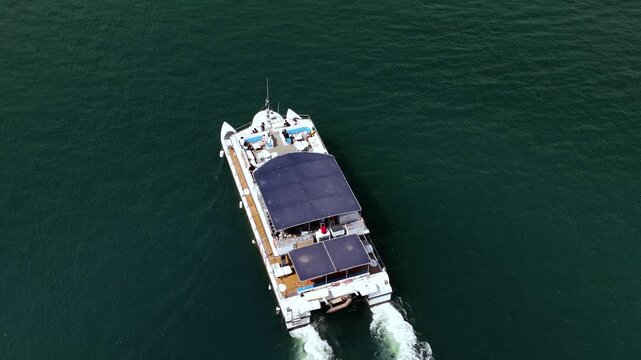 Catamaran boat sailing in deep sea aerial top view. Passenger yacht cruising open ocean water leaving white wake, drone footage. High quality 4k footage