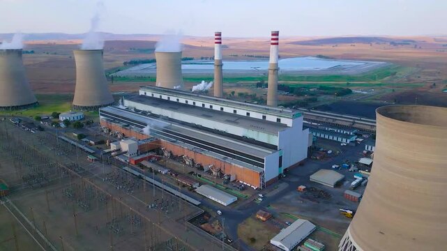 Aerial view of a large coalfired power station with cooling towers and smokestacks in a rural landscape