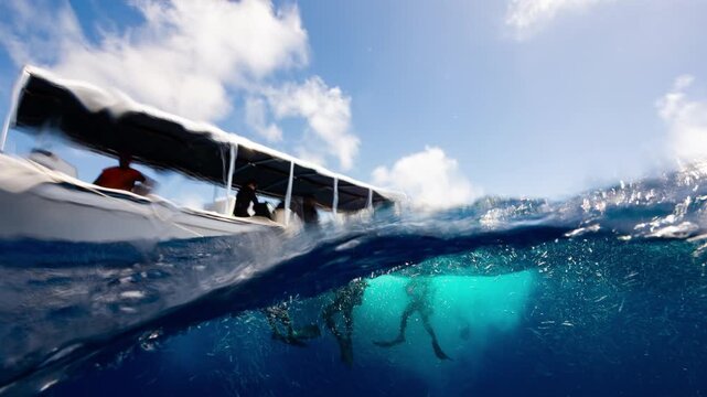 POV underwater shot breaks ocean surface at end of SCUBA Dive to show divers and boat in sunny tropical water	