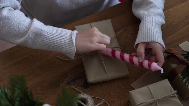 Close up of wrapping pink spiral candle with twine ribbon for holiday gift, close up