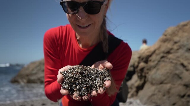 Visitors look at sea glass and rocks at Glass Beach near Mendocino California during a sunny day with ocean views.