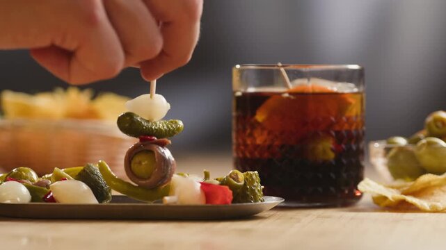 Gilda pintxo, traditional Spanish tapas with hot green pepper, anchovy, olives and pickled vegetables, served with vermouth