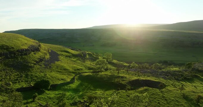 Flying ove a green valley at sunset