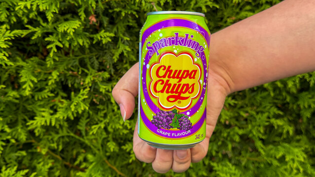 Hand holding chupa chups sparkling grape soda can