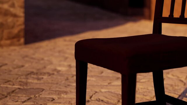 A chair is placed on a stone floor in a room. Evening light casts shadows on the floor and wall, creating a warm atmosphere. The room appears empty and still.
