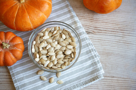 Bowl of raw pumpkin seeds and organic pumpkins