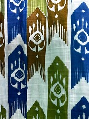 Abstract geometric ikat pattern in blue green and brown on white fabric textile