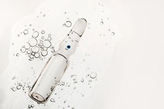 Glass ampoule immersing in clear liquid with many rising bubbles